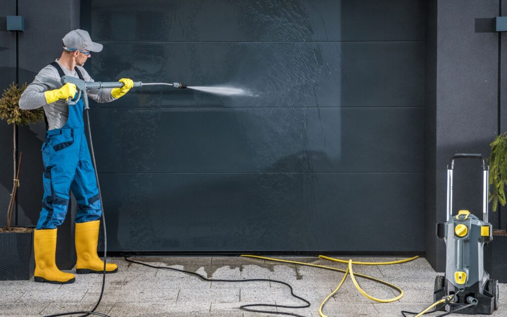 Man cleaning the garage door using power washing for garage cleaning checklist
