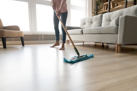 Barefoot woman cleaning floor with wet mop pad cropped image.